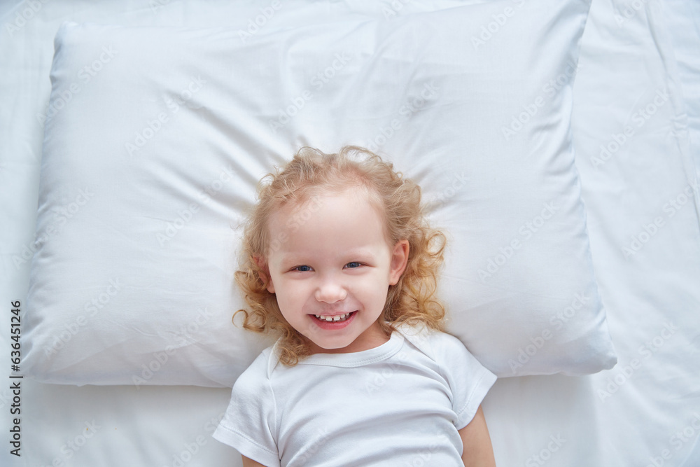 Smiling cute girl on a white pillow. Copy space Smiling cute girl on a white pillow. Copy space