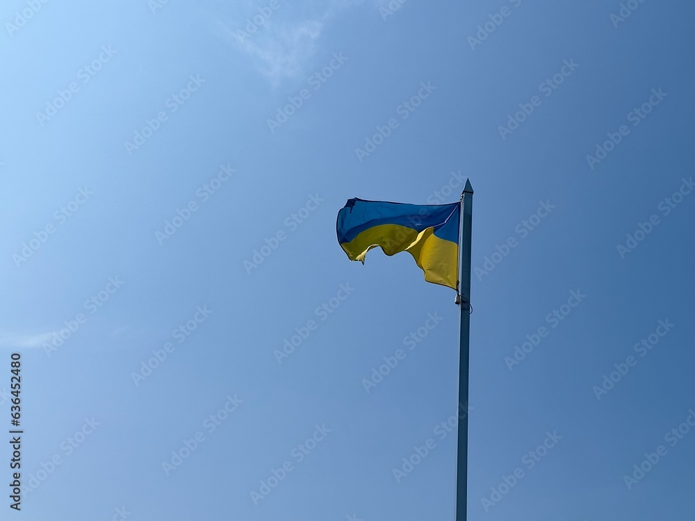 The flag of Ukraine on the flagpole of the building flutters in the wind against the background of a clear blue sky. National flag of Ukraine. Independence Day of Ukraine. The flag of Ukraine on the flagpole of the building flutters in the wind against the background of a clear blue sky. National flag of Ukraine. Independence Day of Ukraine.