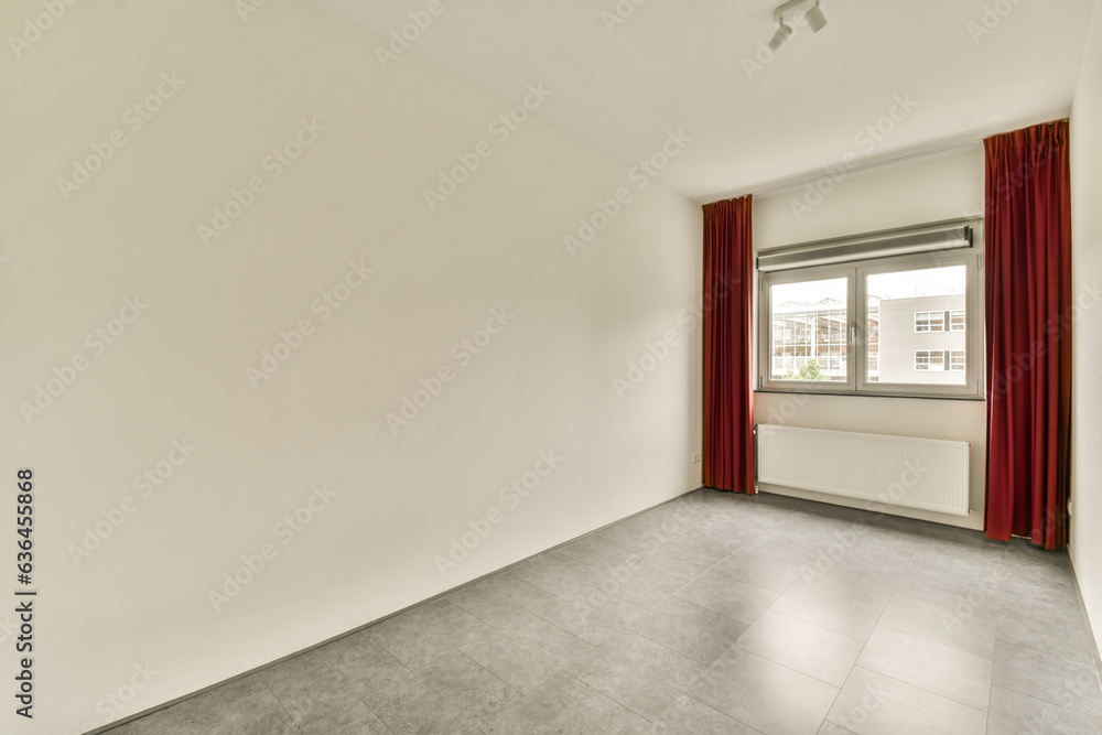 an empty room with white walls and red drapes hanging from the window in it's right hand side an empty room with white walls and red drapes hanging from the window in it's right hand side