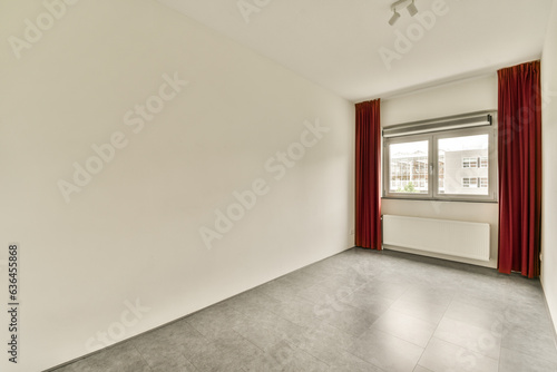 an empty room with white walls and red drapes hanging from the window in it s right hand side