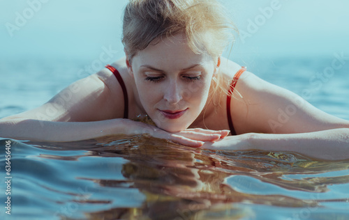 Beautiful blond young woman looking at her reflection in the water