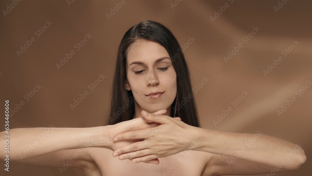 A woman enjoys the velvety and softness of the skin of her hands in the studio on a brown background. The concept of beauty, cosmetology, hand skin care. A woman enjoys the velvety and softness of the skin of her hands in the studio on a brown background. The concept of beauty, cosmetology, hand skin care.