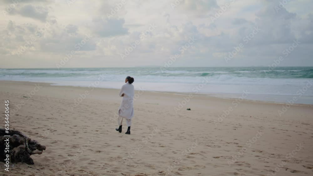Thoughtful woman walking shore on winter day. Peaceful tourist watching ocean Thoughtful woman walking shore on winter day. Peaceful tourist watching ocean