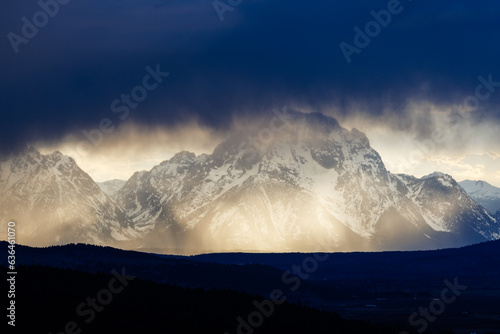 Canvas Print Landscape view of the snow covered Teton Mountains in an opening between the ground and storm clouds in Grand Teton National Park during spring