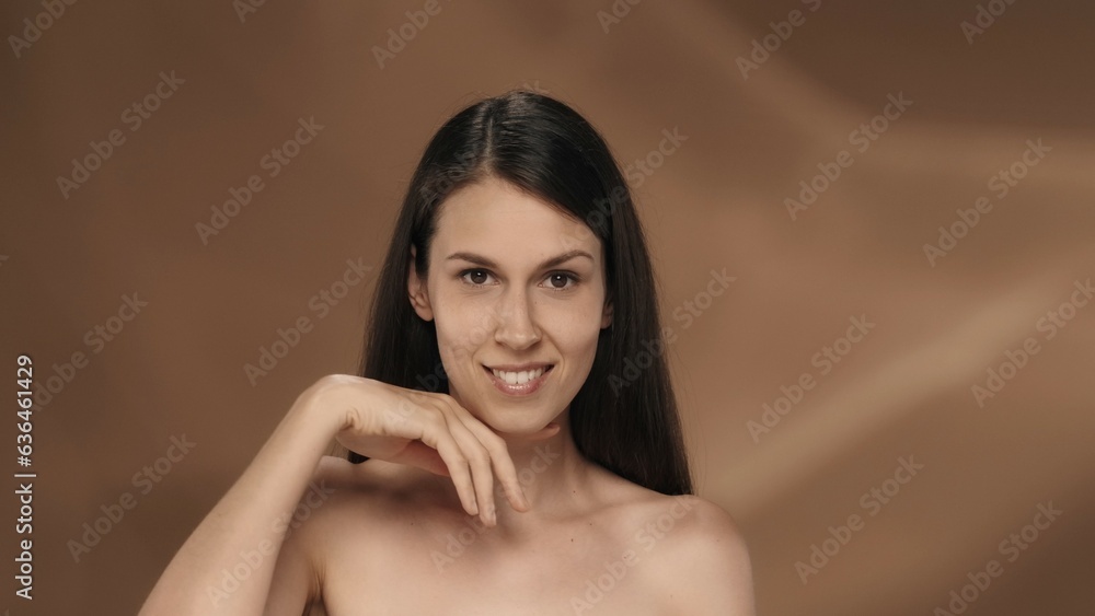 A woman demonstrates her perfect skin and regular facial features. Portrait of a seminude woman on a brown background close up. The concept of natural beauty, plastic surgery, cosmetology, care. A woman demonstrates her perfect skin and regular facial features. Portrait of a seminude woman on a brown background close up. The concept of natural beauty, plastic surgery, cosmetology, care.