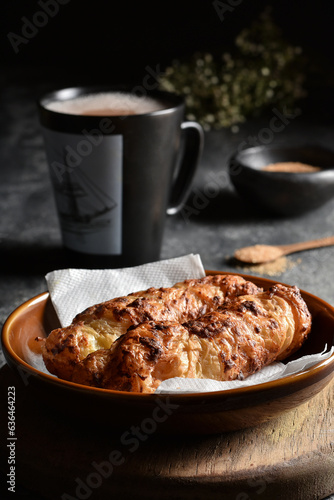 Traditional colombian food, Tequeño or Baked Cheese Stick on a brown plate and black napkin served on a dark table with hot chocolate drink, Dark food lighting