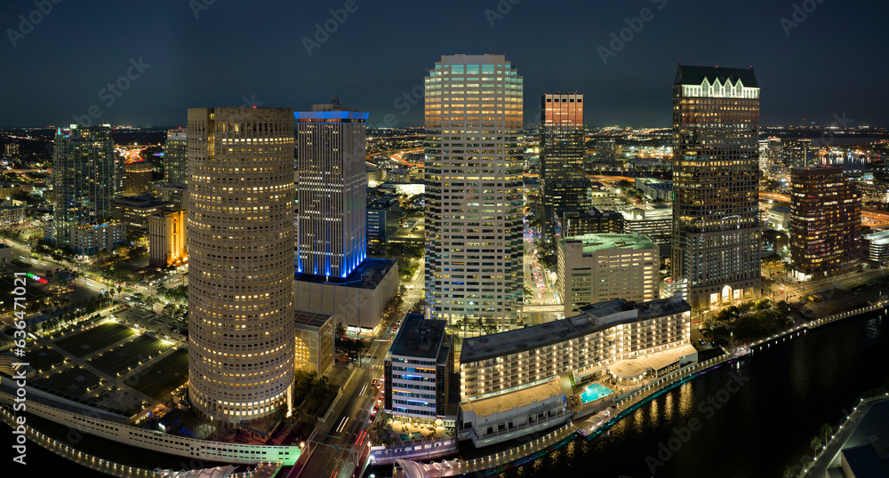 View from above of illuminated skyscraper buildings, pedestrian riverwalk and street traffic in downtown of Tampa city in Florida, USA. American megapolis with business financial district at night