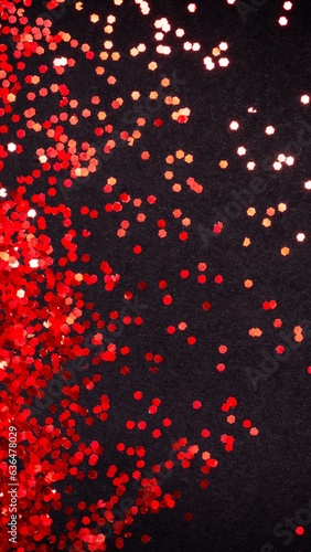 Red glitter on black paper background with copy space, flat lay