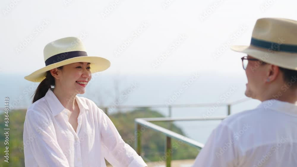 Happy Asian family couple walking together on mountain peak coastline at tropical island in sunny day. Husband and wife enjoy and fun outdoor lifestyle travel nature ocean on summer holiday vacation. Happy Asian family couple walking together on mountain peak coastline at tropical island in sunny day. Husband and wife enjoy and fun outdoor lifestyle travel nature ocean on summer holiday vacation.