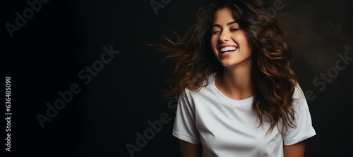 Young woman wearing a white shirt on dark background, mockup model, looking confident, space left for text and logo