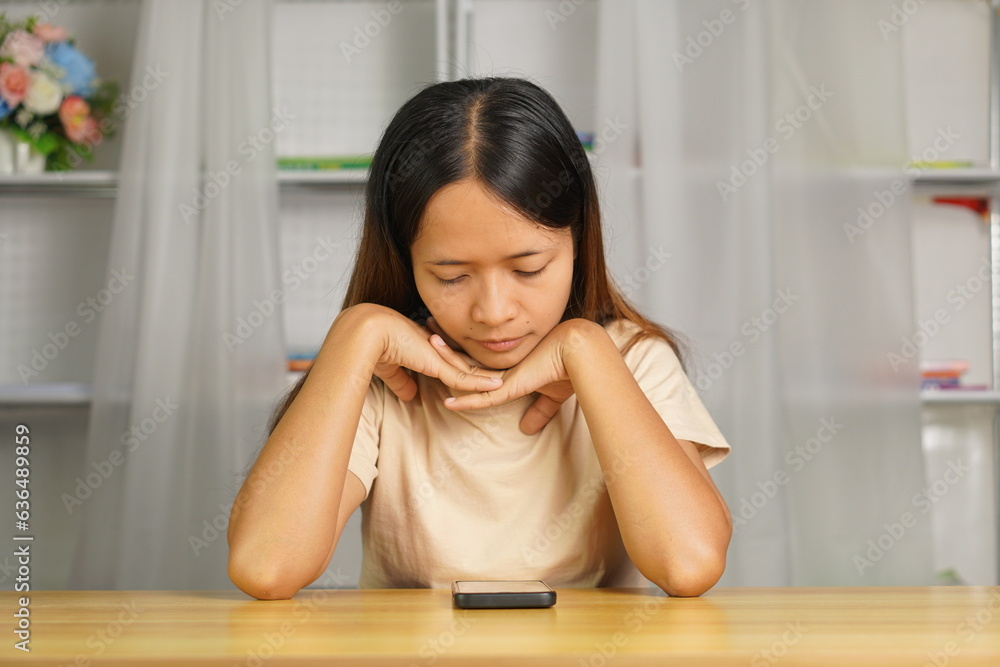 Woman using phone looking at investment profits at home office desk I miss the loss from investment. Woman using phone looking at investment profits at home office desk I miss the loss from investment.