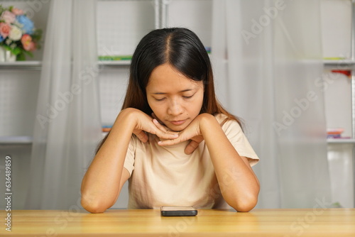 Woman using phone looking at investment profits at home office desk I miss the loss from investment.