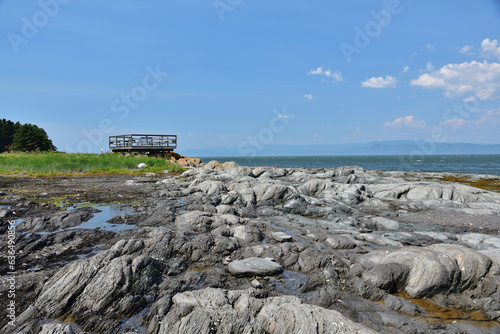 Wooden observatory platform on Island cape on a sunny day. Rocks rounded by the ocean. Ile aux Lièvres on St-Lawrence river photo