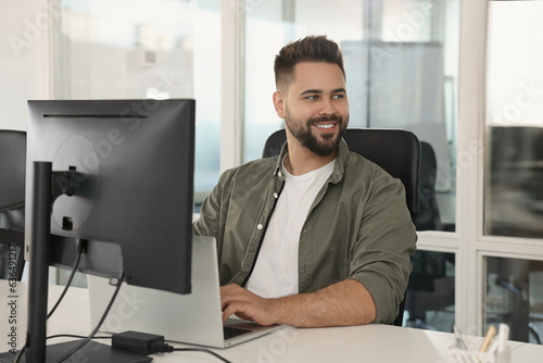 Happy man working on laptop in open plan office photo