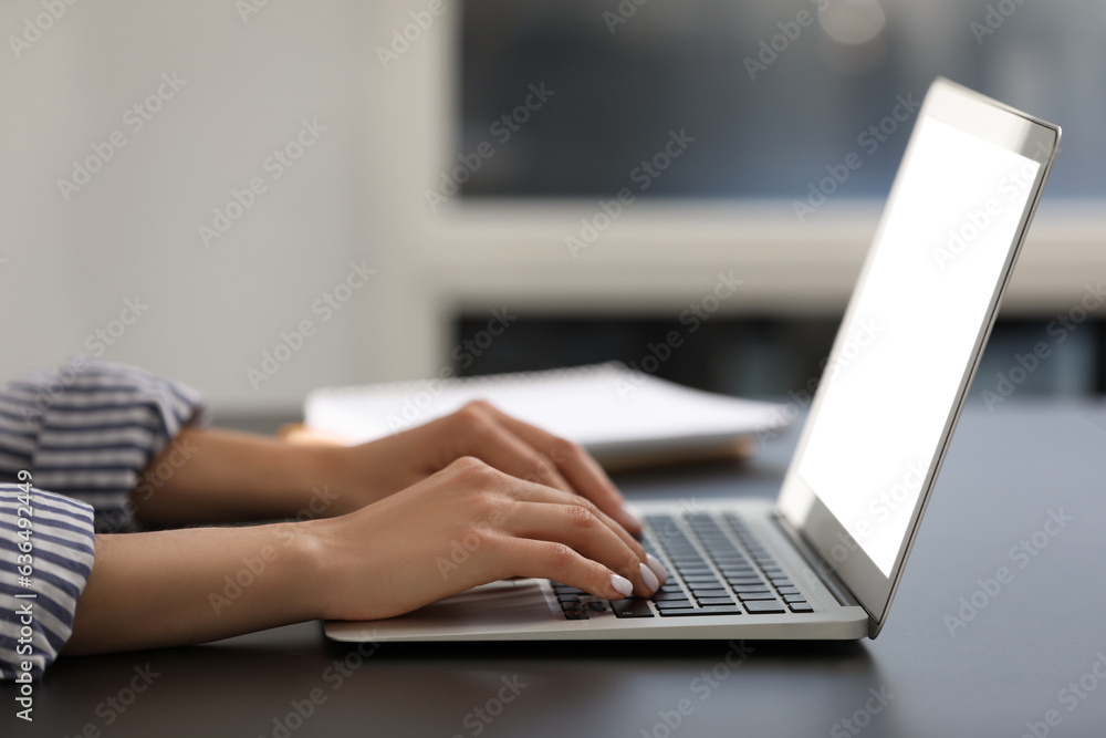 Woman using modern laptop at black desk in office, closeup Woman using modern laptop at black desk in office, closeup