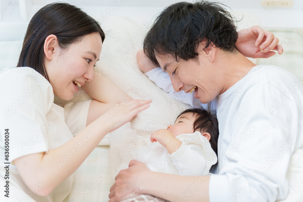 Obraz premium ベッドで赤ちゃんと添い寝する夫婦