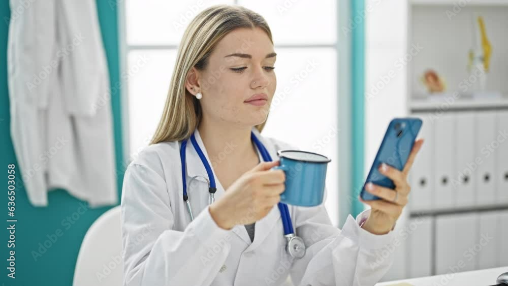 Young blonde woman doctor using smartphone drinking coffee at clinic Young blonde woman doctor using smartphone drinking coffee at clinic