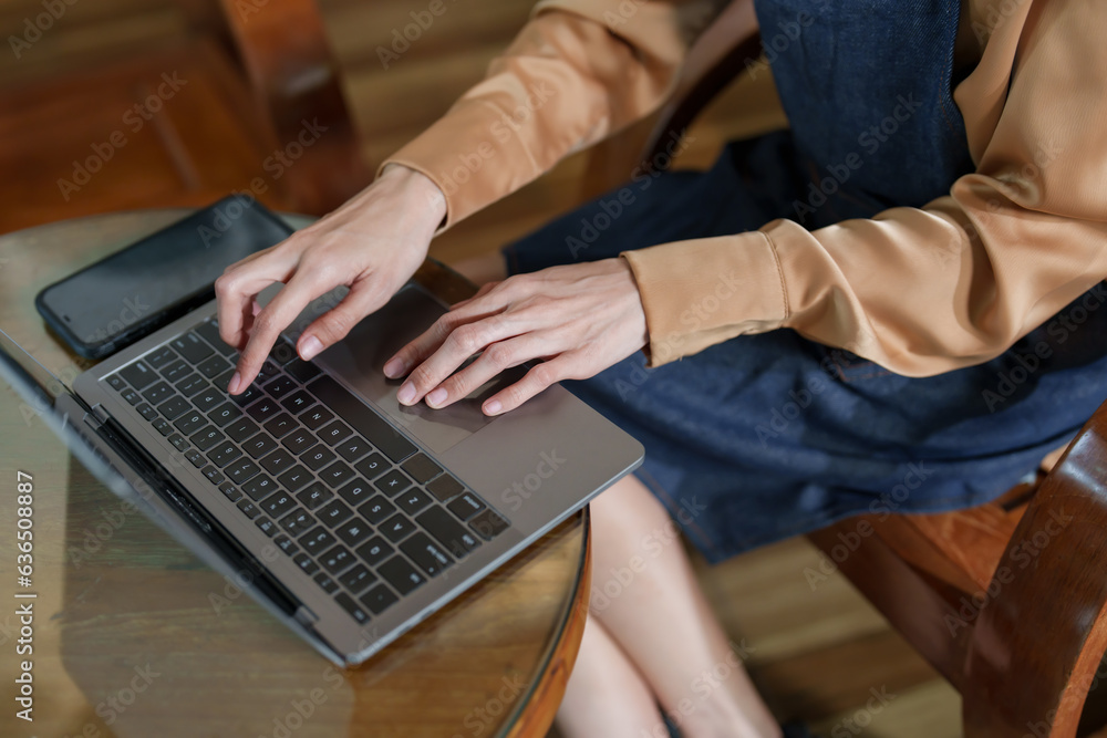 Close-up shot of Asian woman hands in apron sitting using laptop computer. Sitting on the bookkeeping of store, after closing the store, pressing the keyboard of a laptop computer lying on the table. Close-up shot of Asian woman hands in apron sitting using laptop computer. Sitting on the bookkeeping of store, after closing the store, pressing the keyboard of a laptop computer lying on the table.