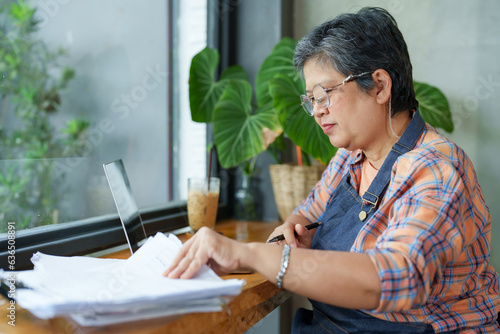 Принти на полотні Asian elderly woman, sitting in front laptop computer screen, using cloth check my glasses, clean eyeglasses, before putting them on wear glasses before working for good vision prevent blurred vision