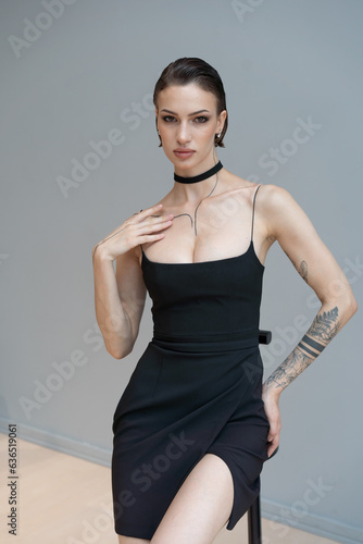 young beautiful woman posing in a black short dress in the studio