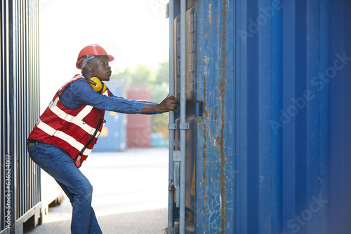 African factory worker or foreman opening the container door in warehouse storage