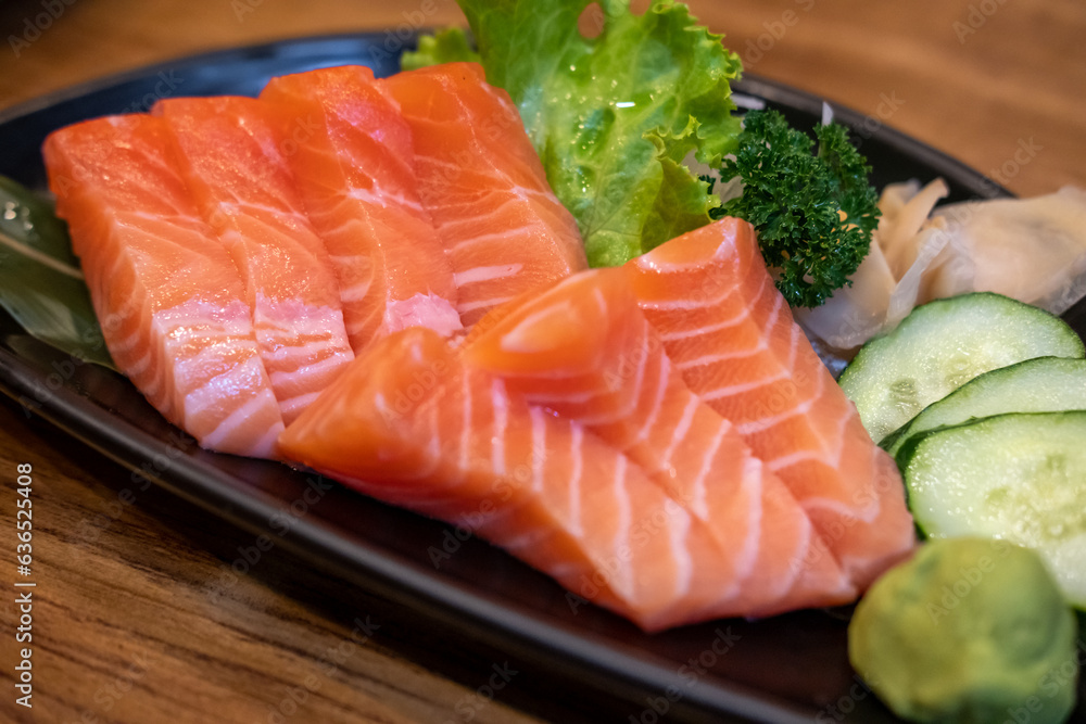 Salmon sashimi with vegetable on plate, served in a restaurant