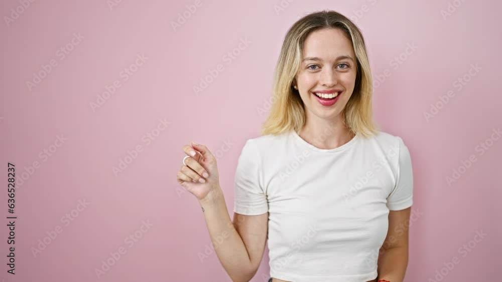 Young blonde woman smiling pointing to the side with finger surprised over isolated pink background Young blonde woman smiling pointing to the side with finger surprised over isolated pink background