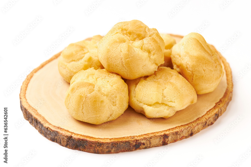 Pile of Cream puffs (Choux cream or Eclair) served on wooden plate isolated on white background. Cream puffs are made with a light choux pastry that puffs up when baked. filled with vanilla cream.