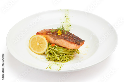 Spaghetti Pesto Sauce with grilled salmon Served with sliced lemon, beautifully decorated with flowers in white dish isolated on white background. Spaghetti with Italian Basil as the main ingredient.