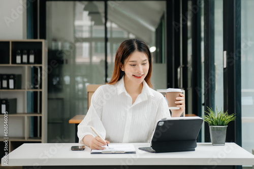 Asian businesswoman working in the office with working notepad, tablet and laptop documents .