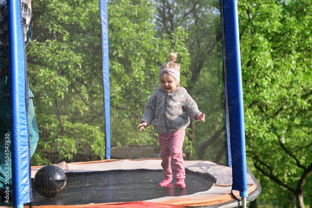 Grandfather and his granddaughter are playing on the trampoline