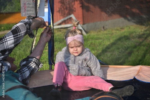 Grandfather and his granddaughter are playing on the trampoline