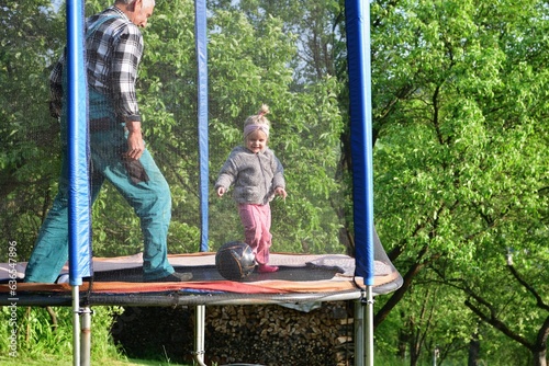 Obraz na płótnie Grandfather and his granddaughter are playing on the trampoline w salonie
