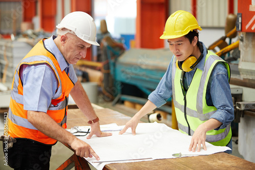 factory workers or engineer planning from work on blueprint drawing paper in the factory