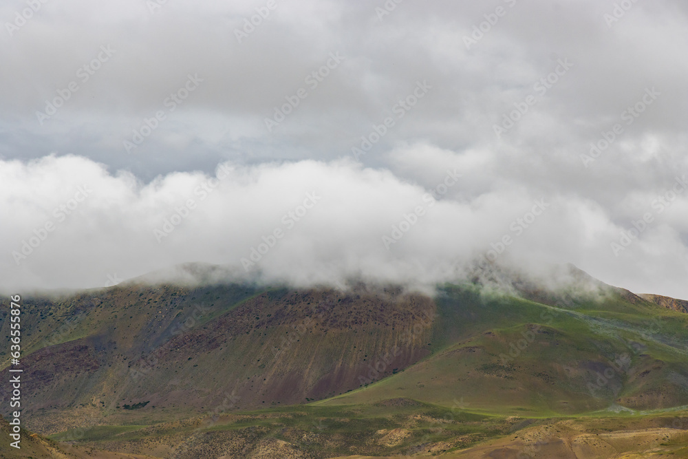 Dark Dramatic Desert Landscape with Foggy Mountains and Distant Houses in Muktinath, Mustang, Nepal Dark Dramatic Desert Landscape with Foggy Mountains and Distant Houses in Muktinath, Mustang, Nepal