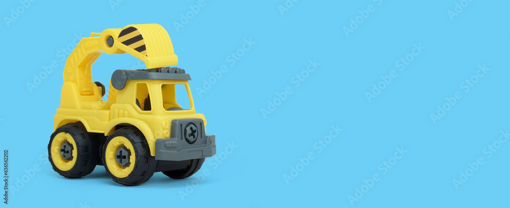 Yellow plastic truck toy isolated on blue background. construction vechicle truck. a copy space for banner of toy store.