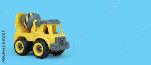 Yellow plastic concrete mixer truck toy isolated on blue background with copy space for banner of toy store.