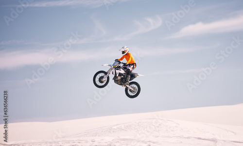 Motorcycle, sky and jump with a man in the desert riding a vehicle for adventure or adrenaline. Bike, speed and training on sand with an athlete in the air in nature for freedom or active competition
