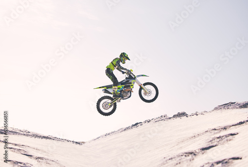 Bike, sand and jump with a sports man riding a vehicle in the desert for adventure or adrenaline. Motorcycle, training and ramp with an athlete outdoor in nature for freedom, power or competition © D Theron/peopleimages.com