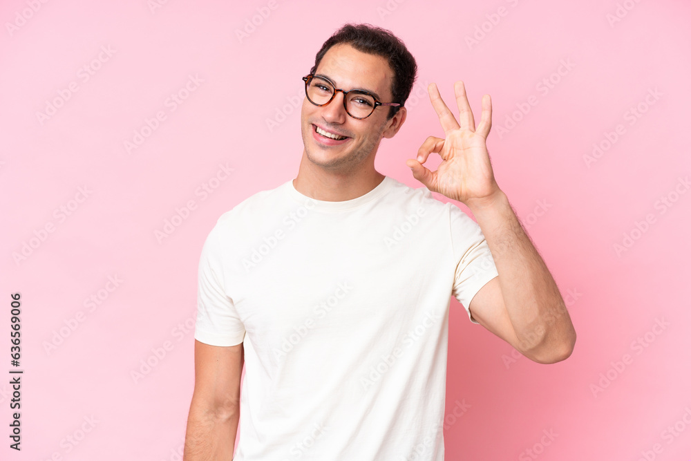 Young caucasian man isolated on pink background showing ok sign with fingers Young caucasian man isolated on pink background showing ok sign with fingers