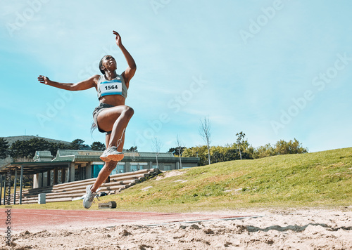 Athletics, fitness and sports woman doing long jump in outdoor competition, athlete challenge or workout. Agility, sand pit and female person training, exercise and action performance at arena event photo