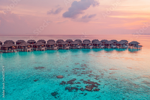 Aerial sunset on Maldives island, luxury water villas resort. Beautiful sky clouds beach nature background. Summer vacation, exotic panoramic travel. Colorful seascape reef coast, inspire landscape 