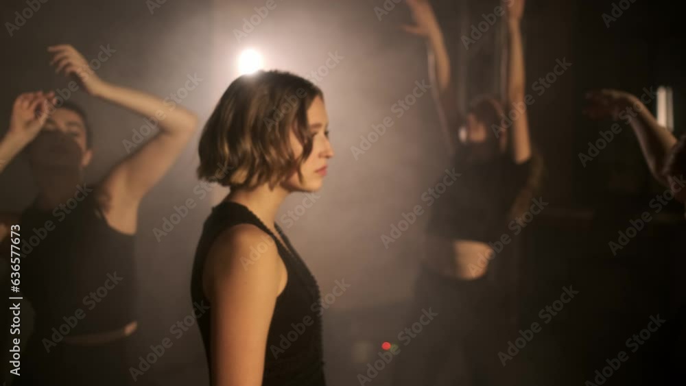 A young beautiful girl walks between the dancing people and watches them. The concept of modern dance. Graceful movements. Beautiful body movements. A young beautiful girl walks between the dancing people and watches them. The concept of modern dance. Graceful movements. Beautiful body movements.