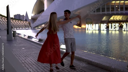 Young positive couple walking holding hands date in city park street, sunset time