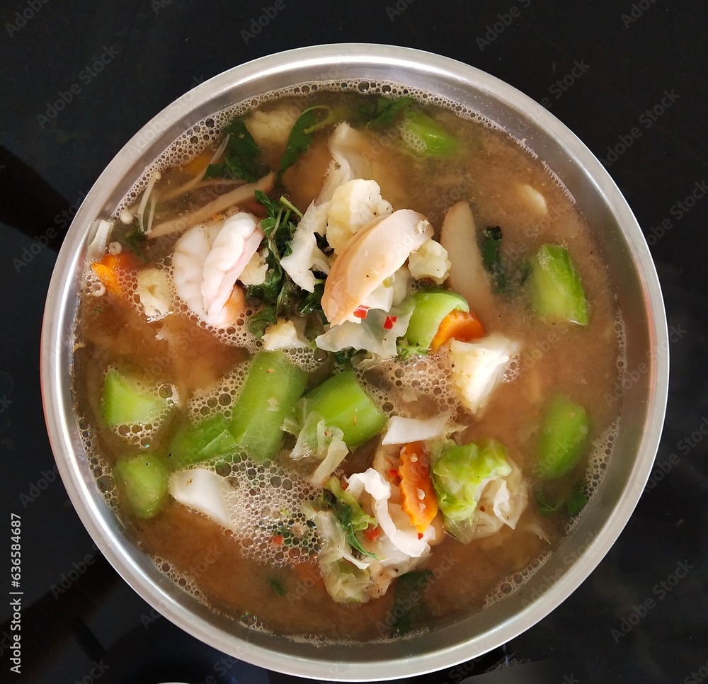 A bowl of curry contains a variety of meat and vegetables.