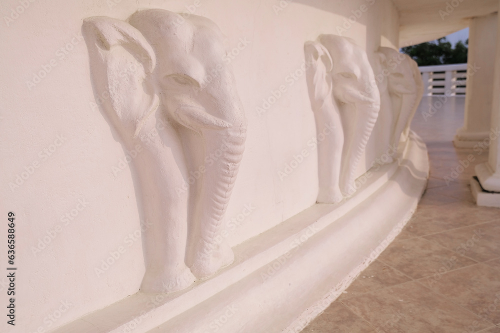 Wall with a bas-relief of elephants on the wall of a Buddhist temple, elephant head sculpture Wall with a bas-relief of elephants on the wall of a Buddhist temple, elephant head sculpture