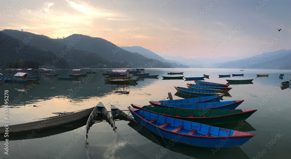 Sunset over Pokhara lake in Nepal with rental canoe boats