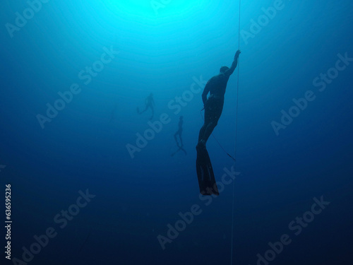 Foto Freediver coming up from a deep dive along the line with divers in background
