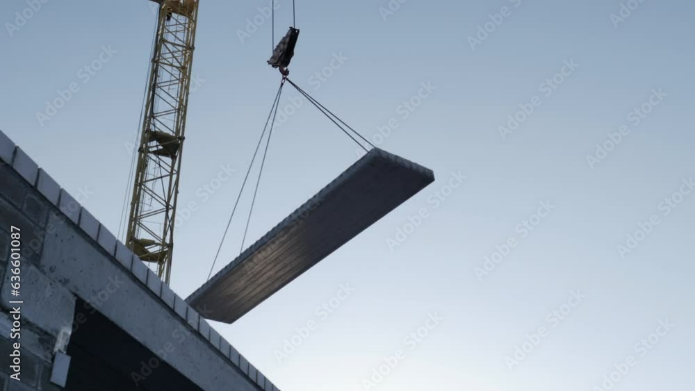 A following shot of a tower crane working at a construction site at daytime A following shot of a tower crane working at a construction site at daytime