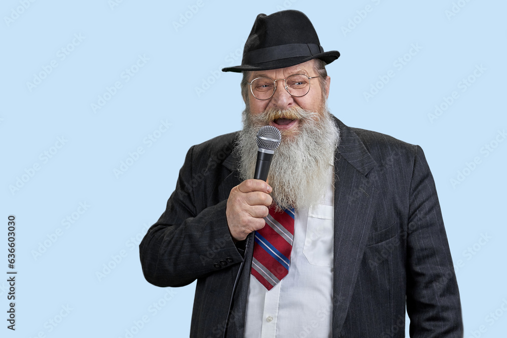 Portrait of excited aged man with microphone. Isolated on blue. Giving a speech. Portrait of excited aged man with microphone. Isolated on blue. Giving a speech.